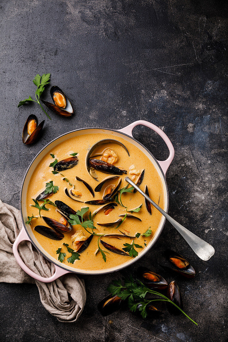 Seafood soup with shrimp and mussel in casserole on dark background