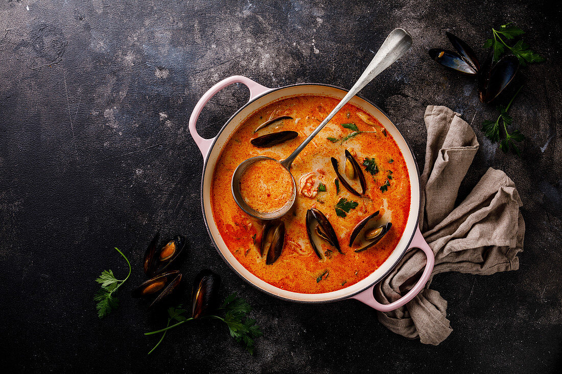 Seafood soup with prawns, mussels and tomato on dark background