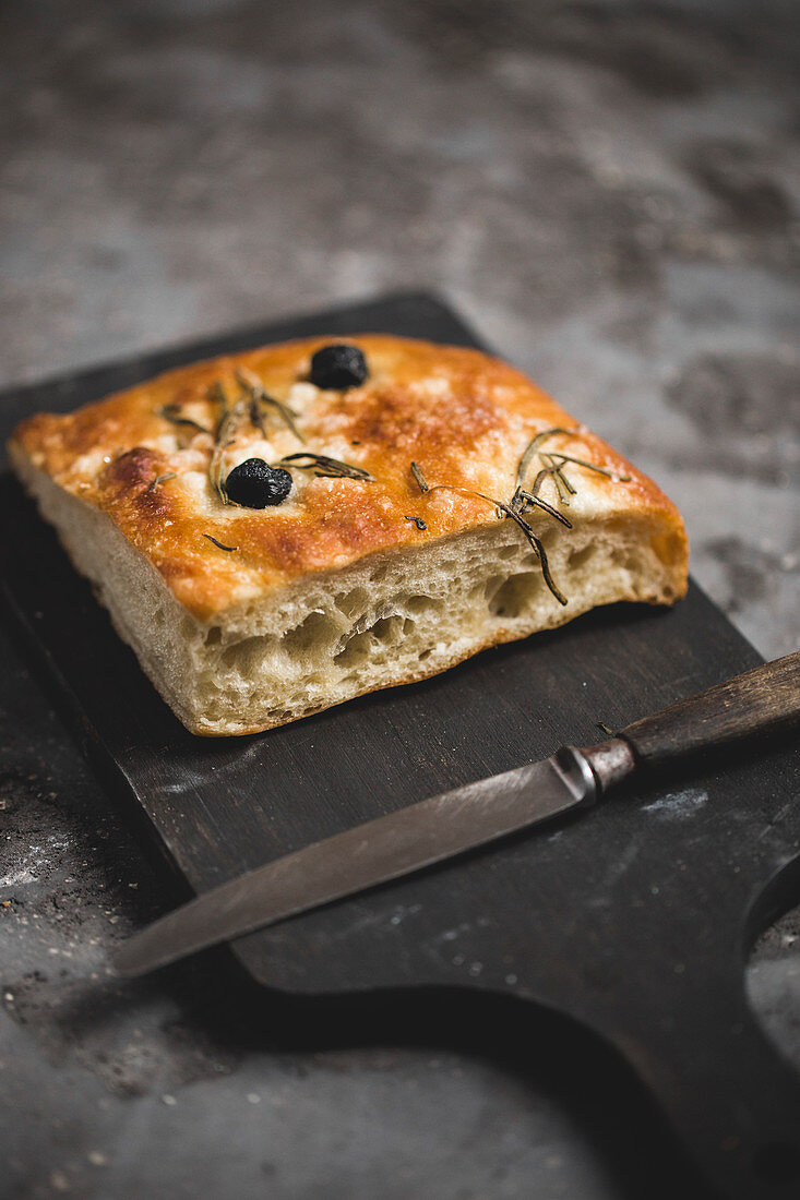 Focaccia with olives and rosemary on a wooden board