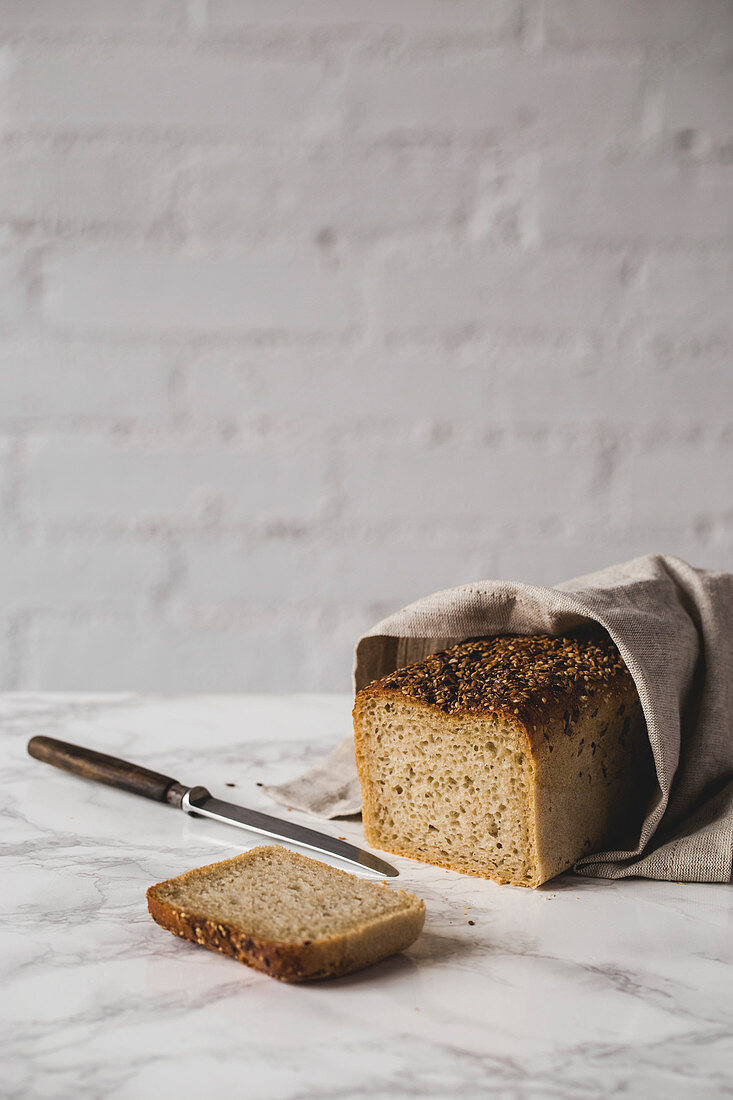 Angeschnittenes Brot in Leinentuch gewickelt auf Marmortisch