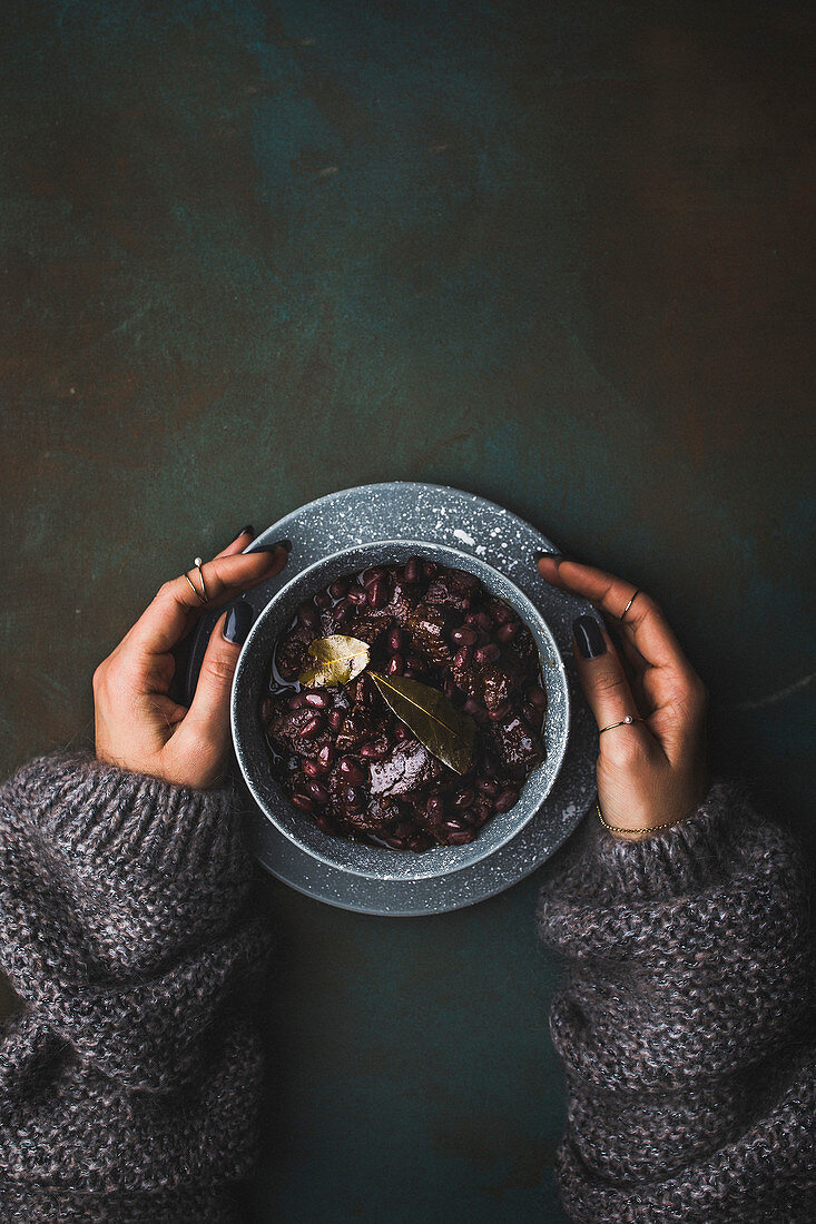 A woman holding a bowl of goulash (seen from above)