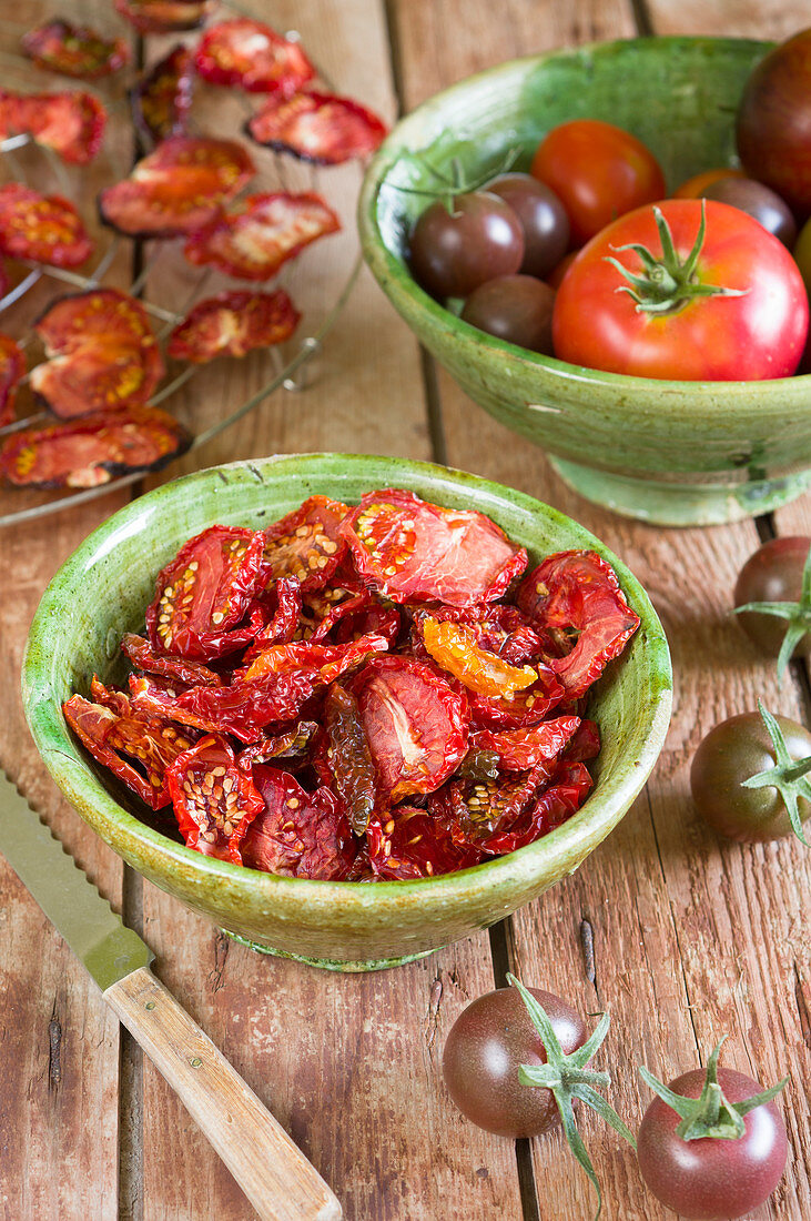 Getrocknete Tomaten auf einem Rost und in Keramikschüsseln