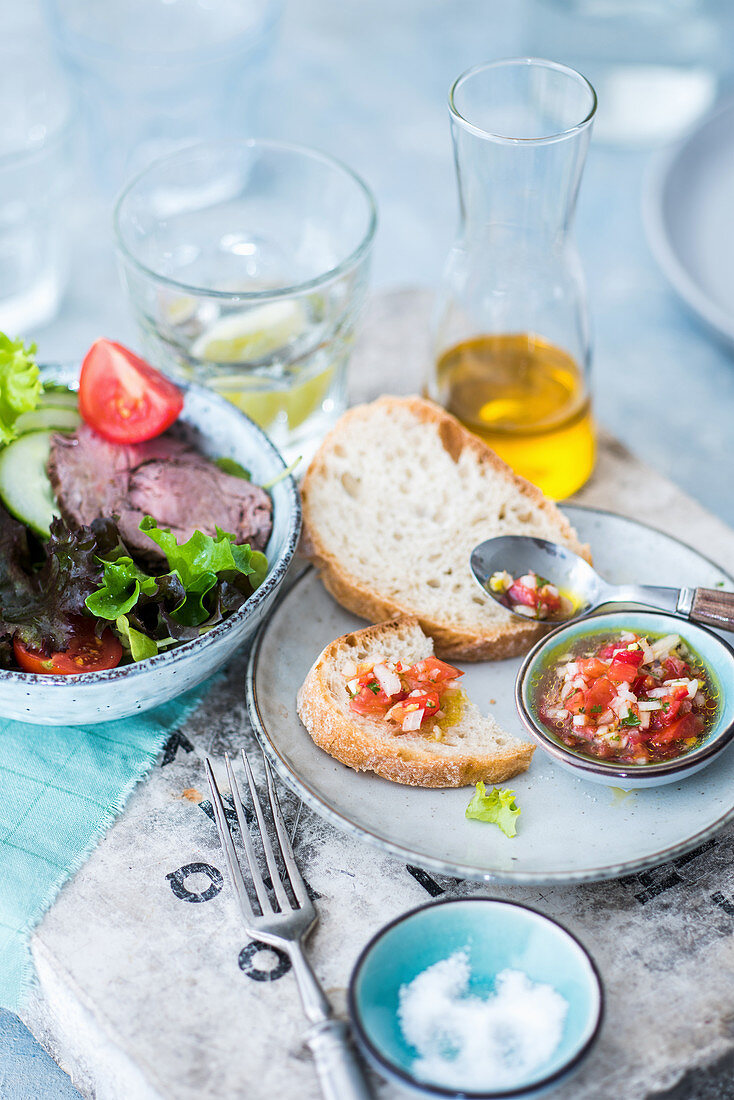 A mixed leaf salad with beef fillet and tomatoes, baguette with tomato chutney