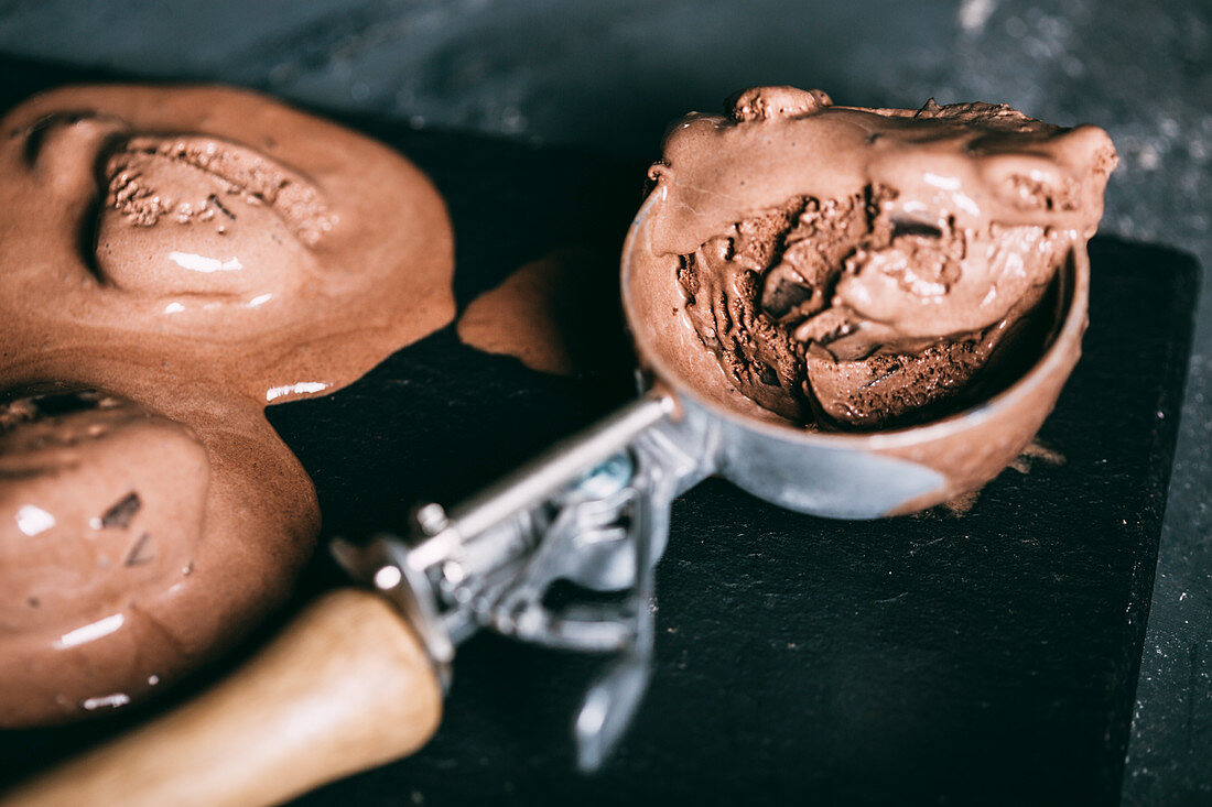 Chocolate ice cream in a scoop on dark background