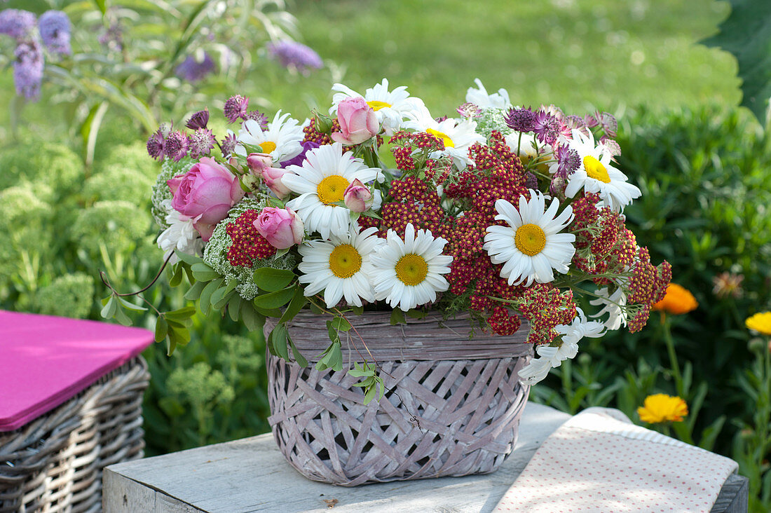 Bouquet of daisies, yarrow and roses in a basket