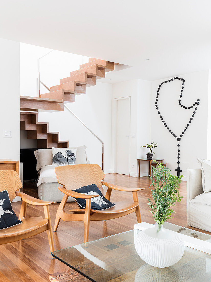 Classic armchairs next to glass table in open-plan interior with staircase in background