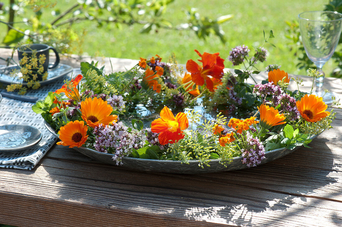 Wreath of edible flowers and herbs in bowl with water
