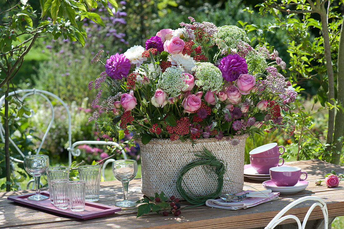 Lush table arrangement made of roses, dahlias, cartilage and yarrow