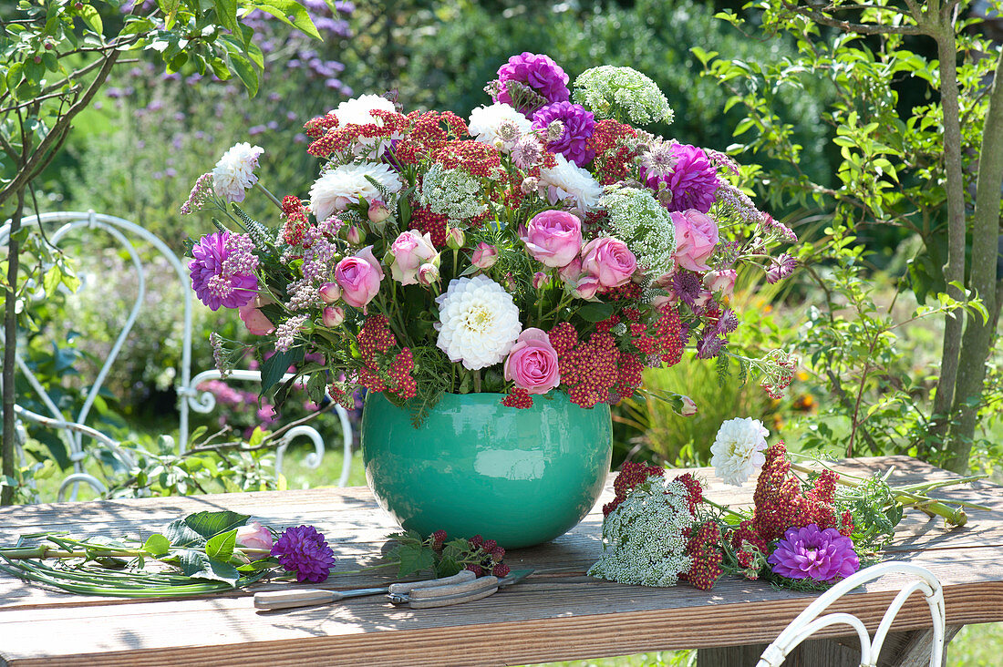 Lush table arrangement made of roses, dahlias, cartilage and yarrow