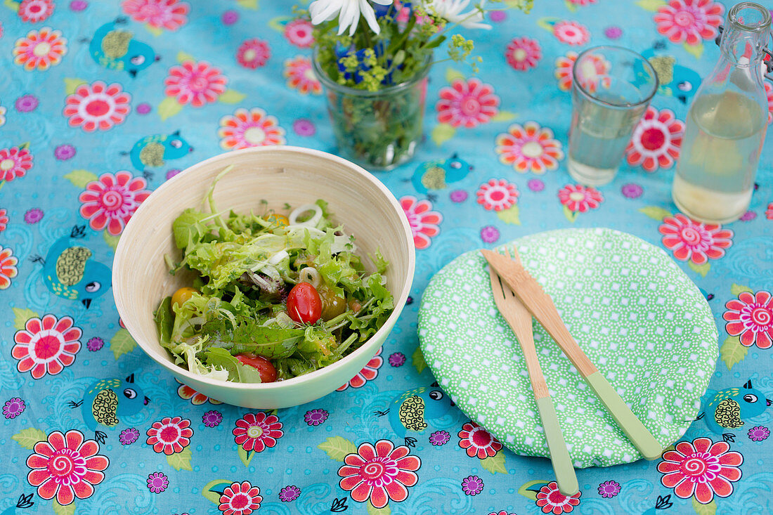 Bowl of salad, handmade oilcloth bowl cover and wooden cutlery