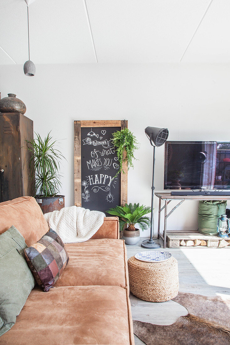 Braunes Ledersofa, im Hintergrund Kreidetafel, Stehleuchte und Vintage Fernsehtisch im Wohnzimmer