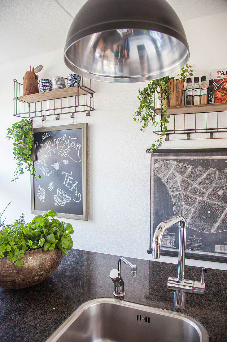 Granite kitchen worksurface with integrated sink, potted herbs and chalkboard on wall