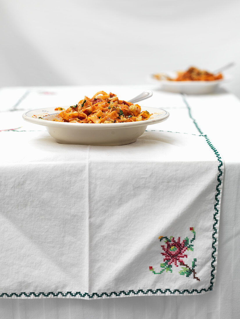 Selbstgemachte Pasta mit Tomaten in Tellern auf Tisch