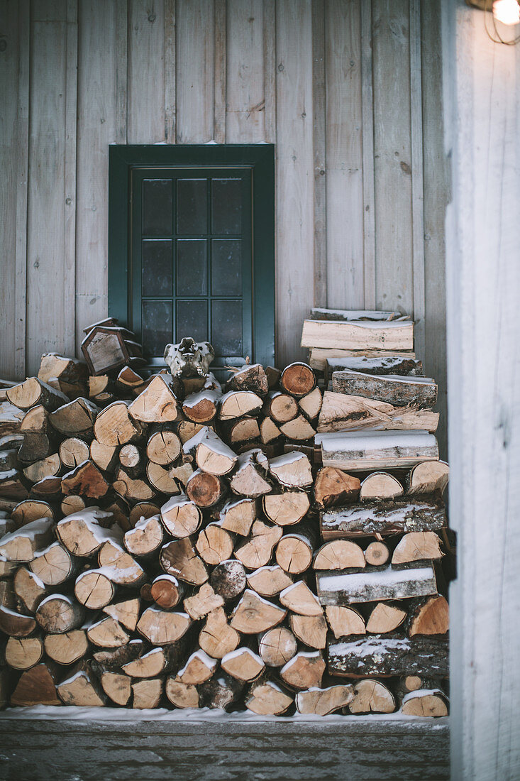 Brennholzstapel an Hauswand im Winter
