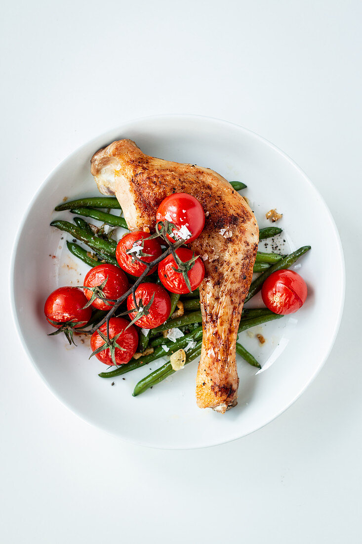 Oven-roasted chicken leg with beans and cherry tomatoes