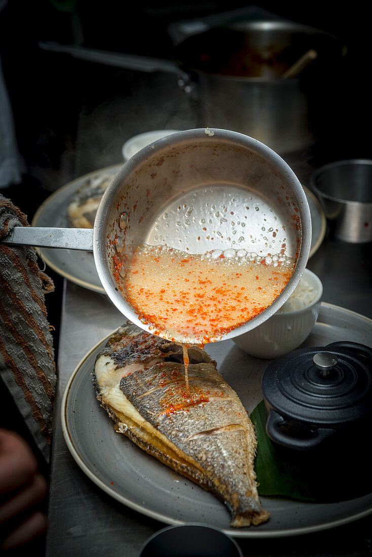 Hot Dressing being poured over Sea Bream