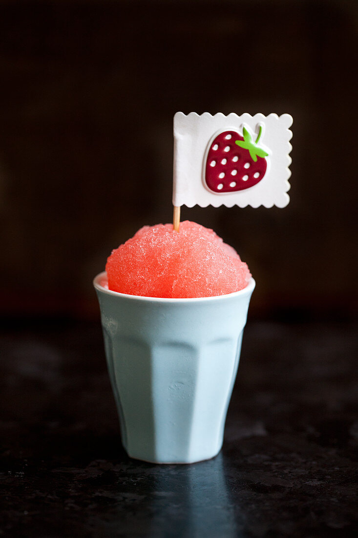 A strawberry snocone (strawberry syrup poured onto crushed ice) with a strawberry sticker flag