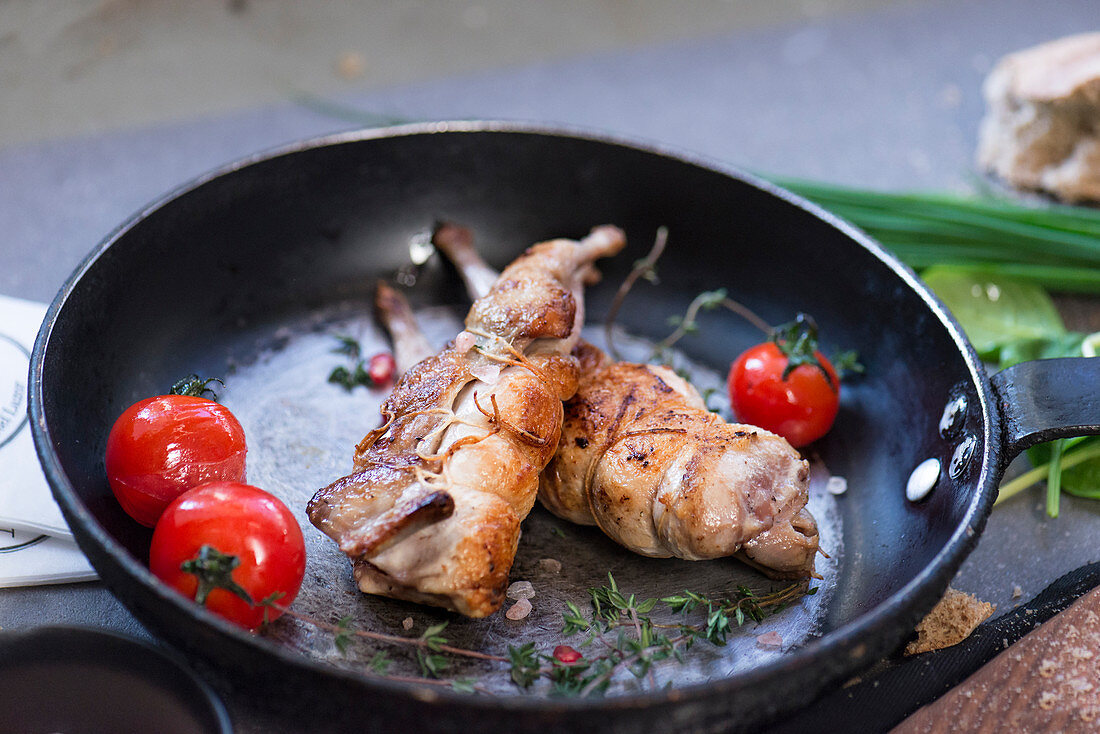 Tasty appetizing poultry served on frying pan with fresh red tomatoes