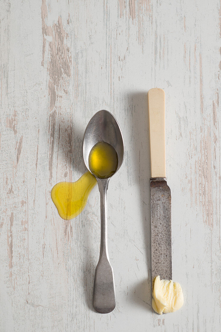 Olivenöl auf Löffel und Butter auf Messer