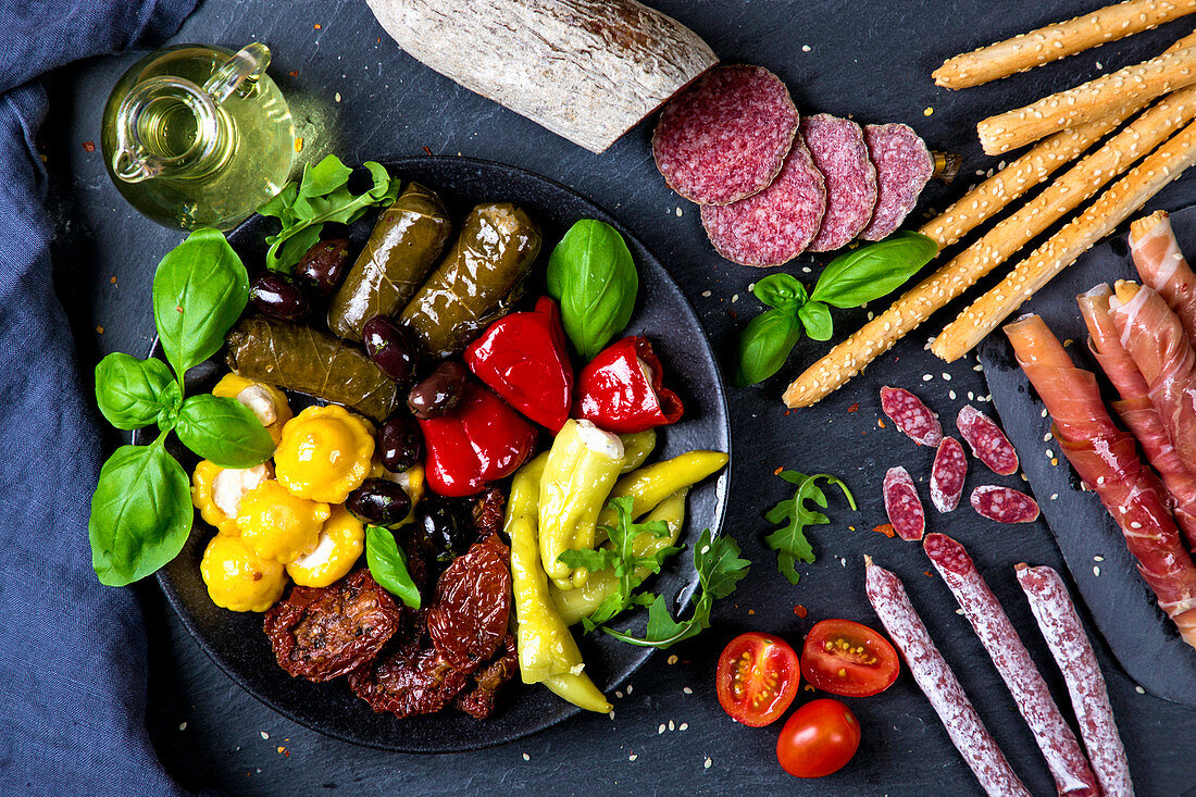 Various Italian antipasti on a black slate board