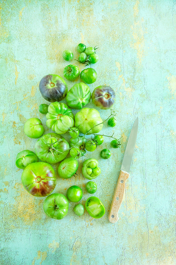 Grüne Tomaten und Messer auf altem Tisch