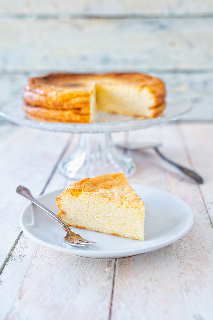 Classic cheesecake on a cake stand and a slice on a plate