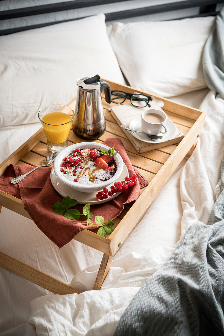 Frühstücktablett mit Chiapudding, Kaffee und Orangensaft im Bett