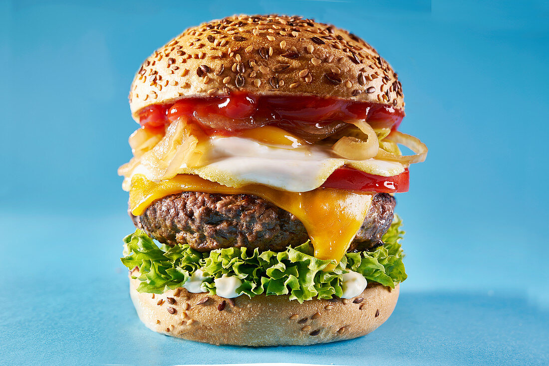 Cheeseburger mit Spiegelei, Ketchup und Zwiebeln