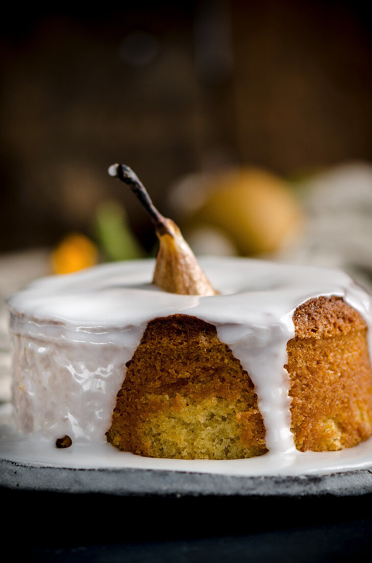 A vanilla cake with a whole baked pear and icing