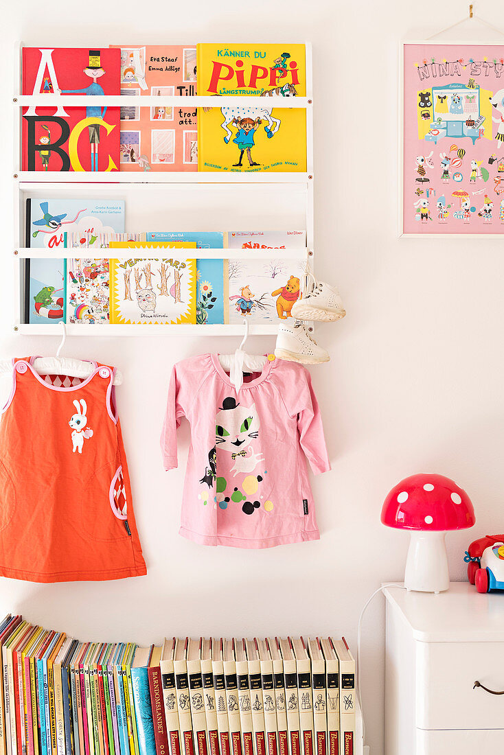 Bookshelves and dresses in bright girl's bedroom