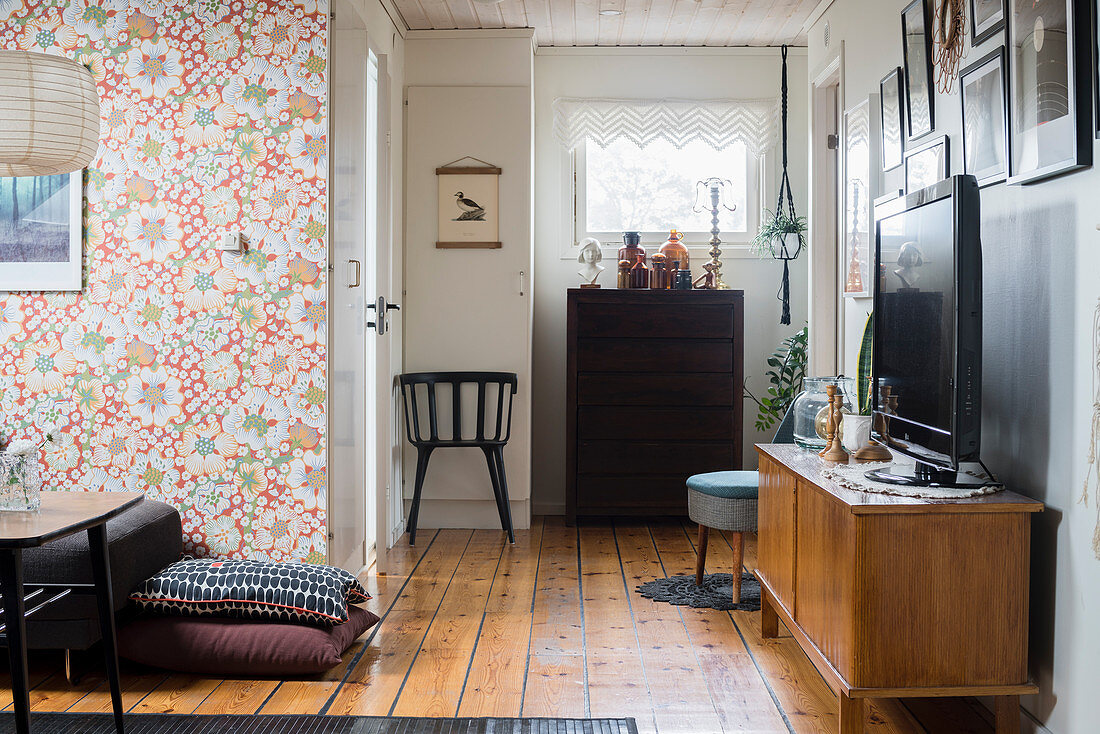 Fernseher auf Sideboard im Zimmer mit Retro-Tapete