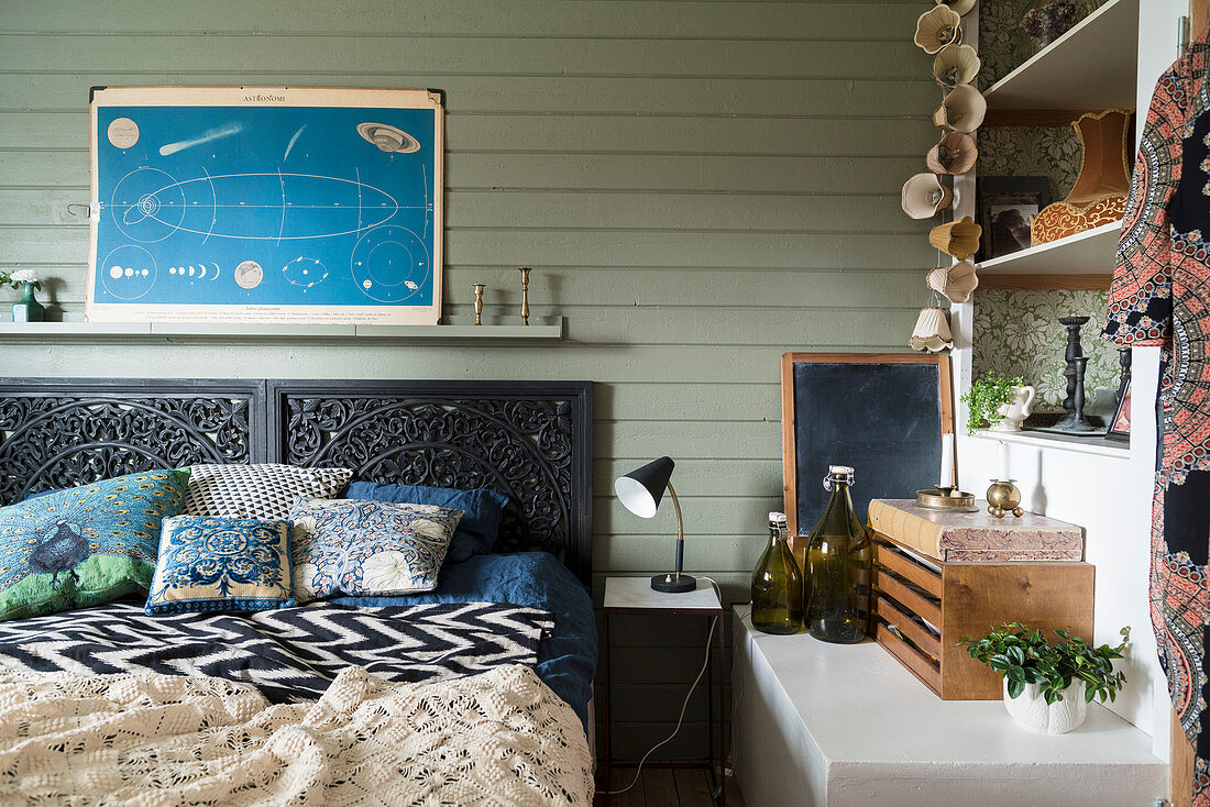 Double bed with black headboard against green-painted wooden wall