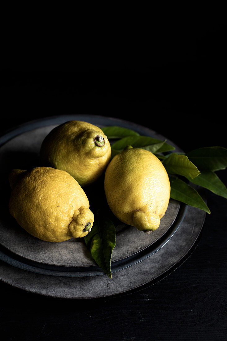 Drei Zitronen mit Blättern auf Teller