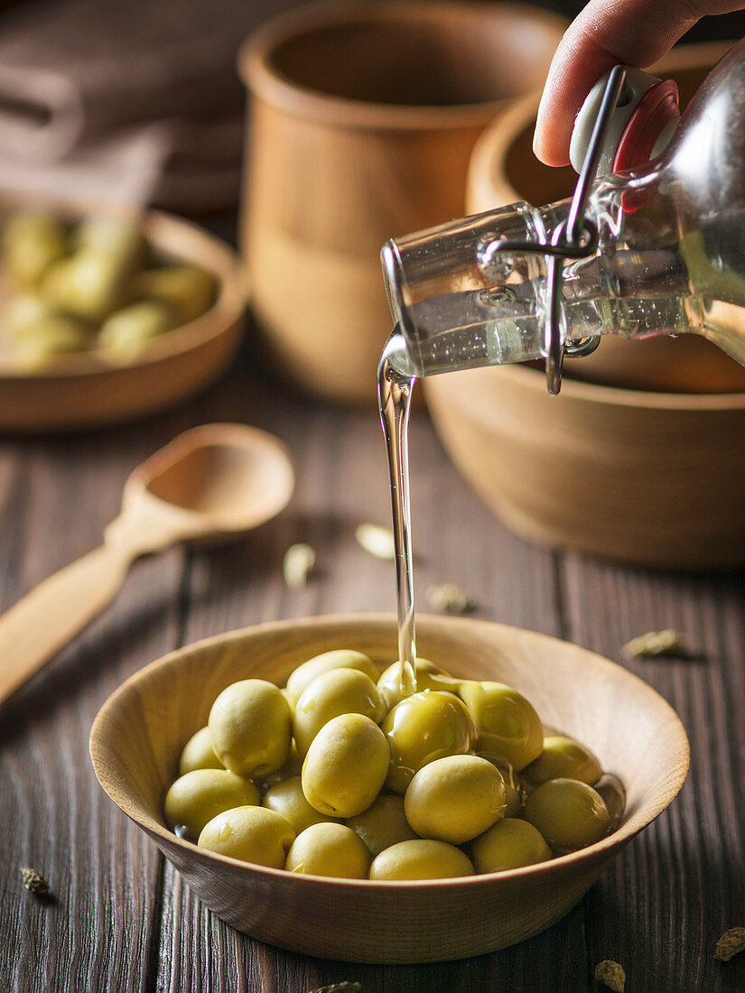 Olivenöl auf grüne Oliven gießen