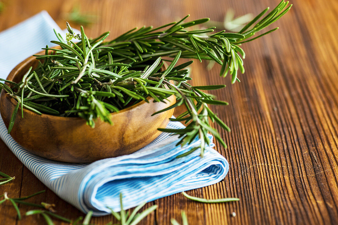 Organic fresh rosemary herb on textile napkin on wooden table