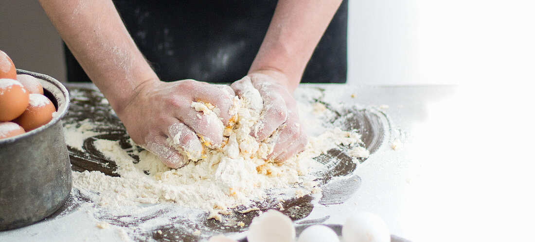 Hands kneading dough on a floured surface