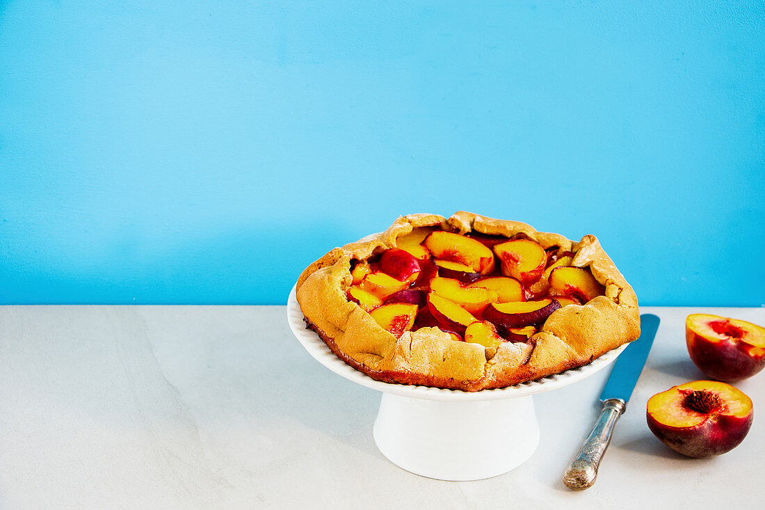 Homemade peach galette on blue background
