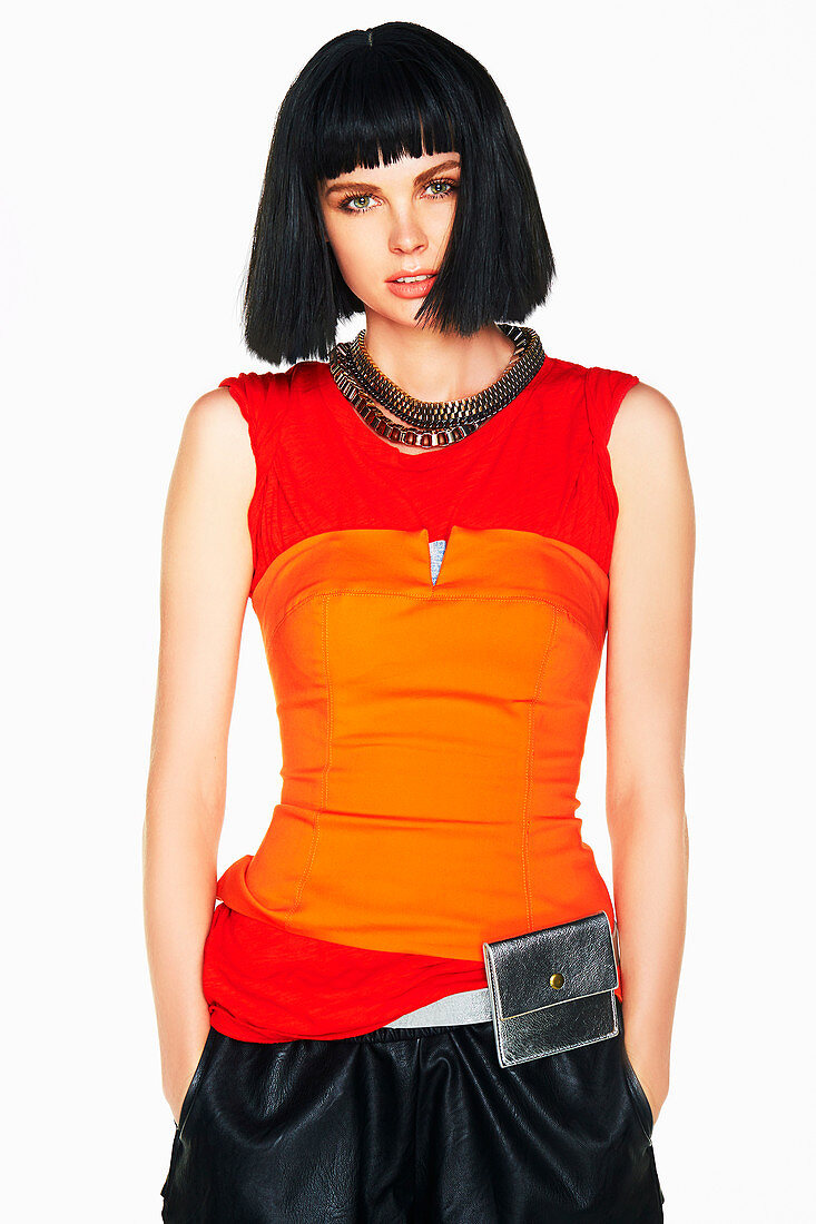 A black-haired woman wearing a long, red top, an orange corset and a black skirt