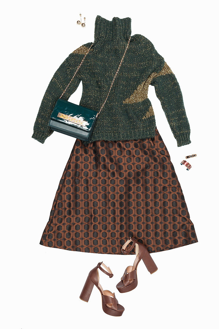 A green knitted jumper with a gold-pattern, a brown skirt with a retro pattern and sandals