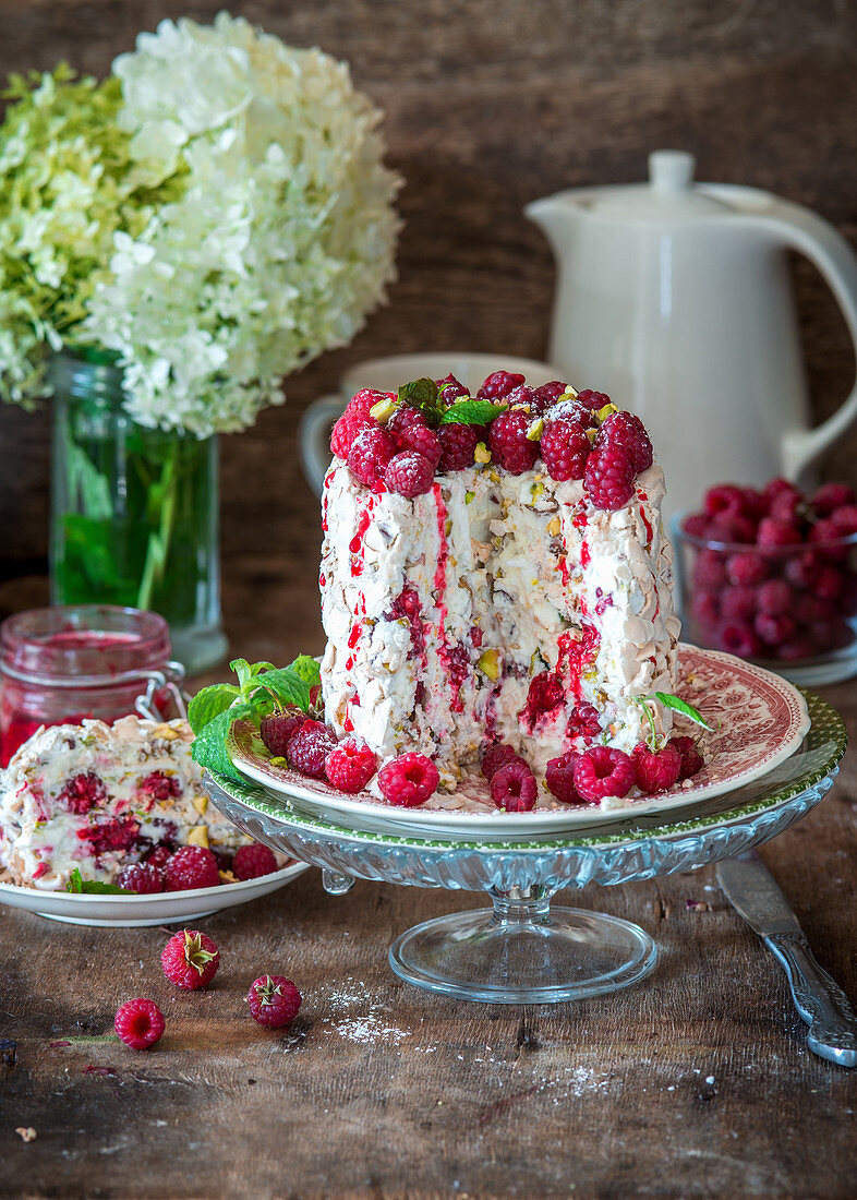 Vertical meringue roll cake with pistachios and raspberries