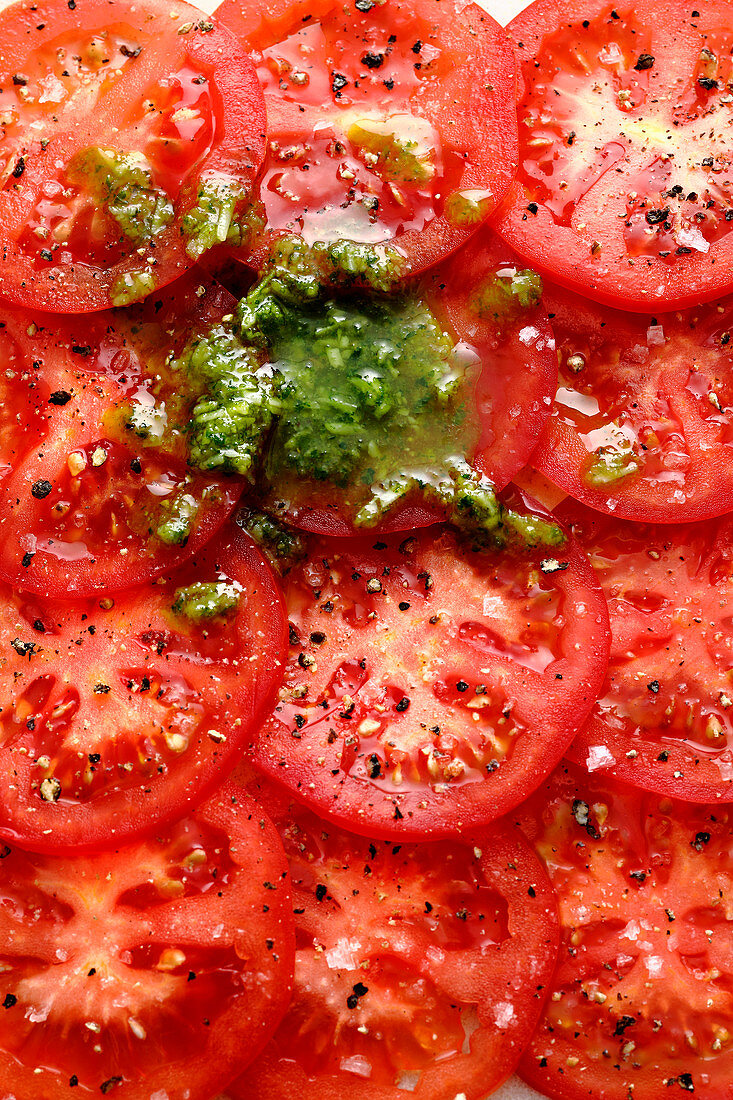 Tomato slices with salt, pepper and pesto (close-up)