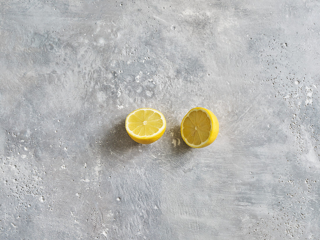A halved lemon on a grey stone surface