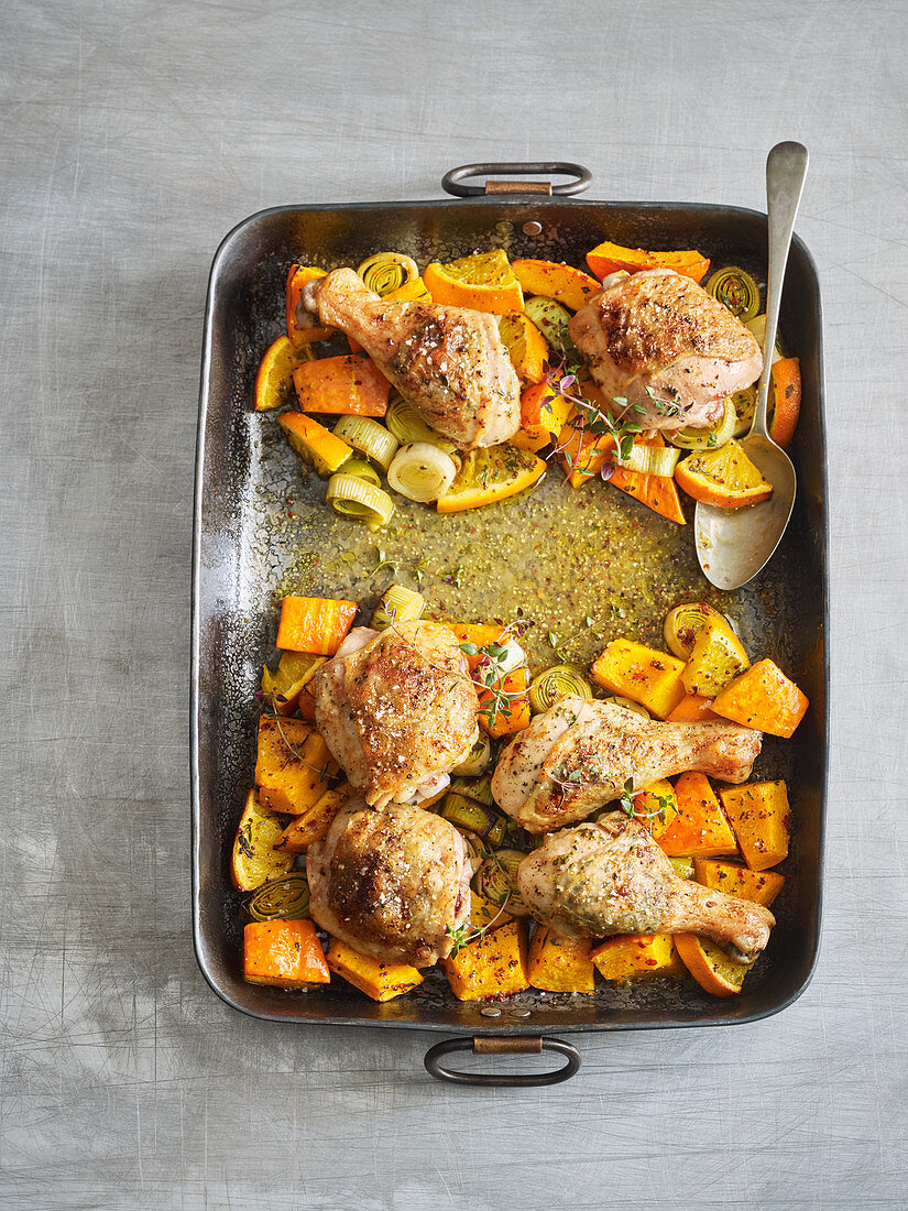 Chicken with pumpkin and leek on a baking tray