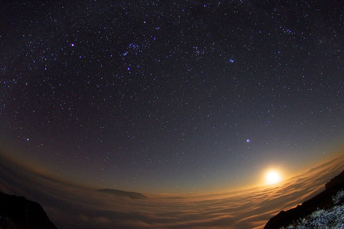 Moon setting over clouds