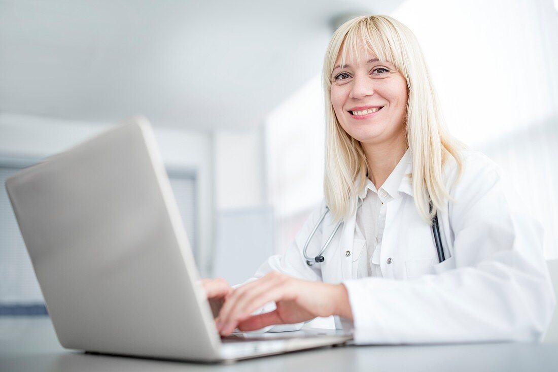 Doctor using laptop and smiling