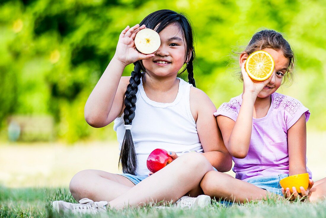 Girls sitting and holding various fruits