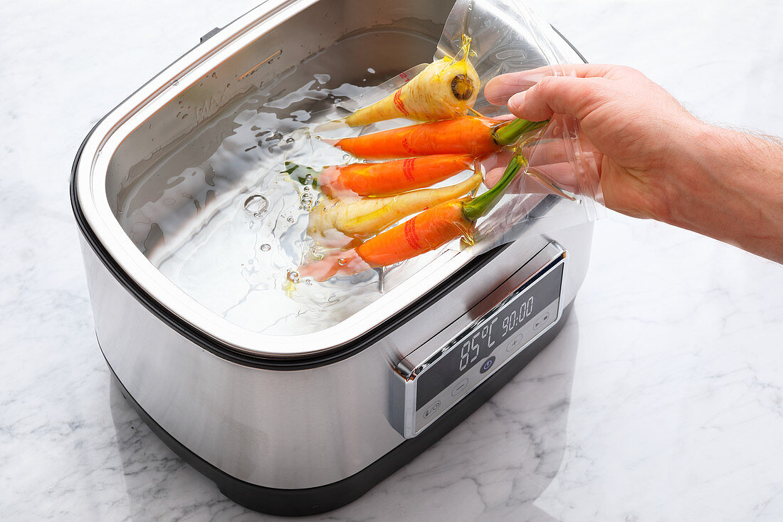 Sous vide root vegetables being placed in a sous vide cooker