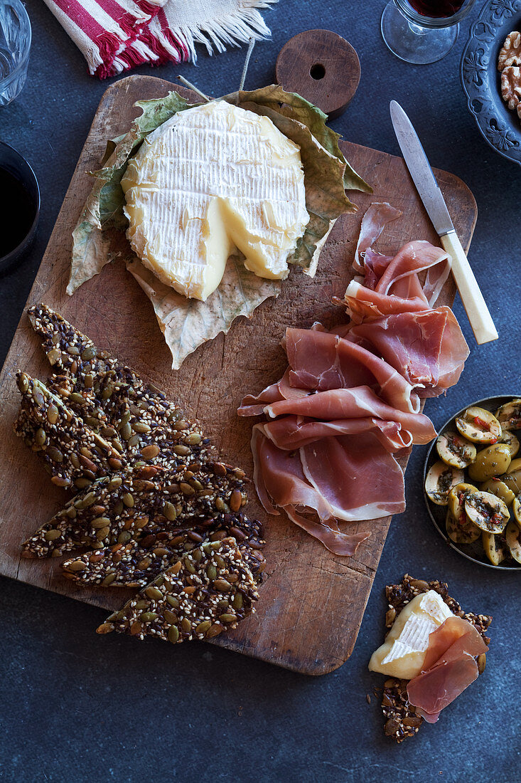 An appetizer platter with soft cheese, ham, olives and crackers (keto cuisine)