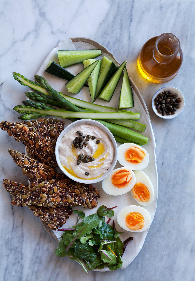 An appetizer platter with crackers, vegetables, eggs and a tuna fish dip (keto cuisine)