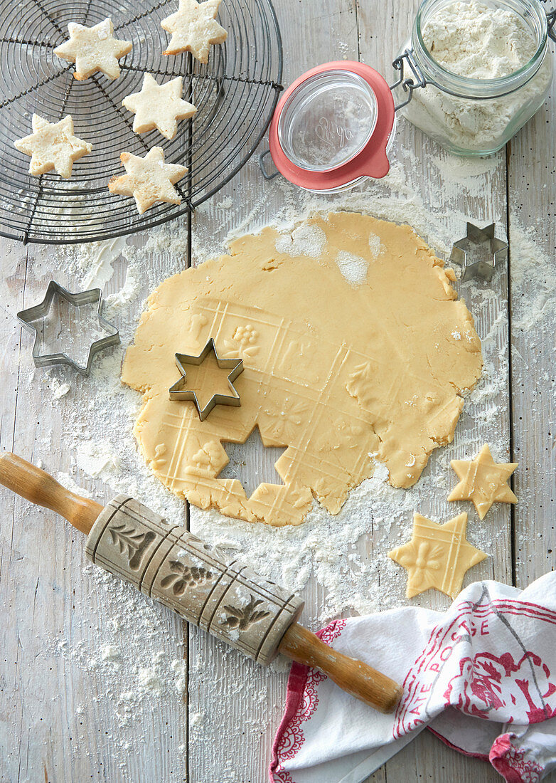 Cookie dough with cutters and a rolling pin on a floured wooden table